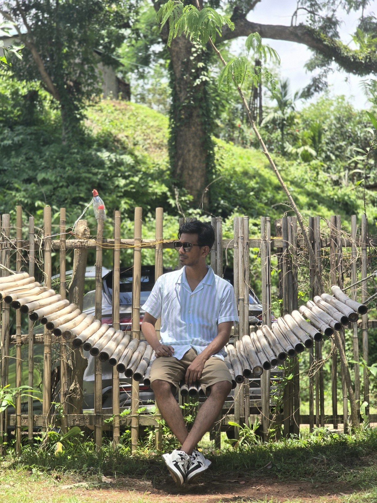 Sitting on a curved bamboo bench near a wooden fence