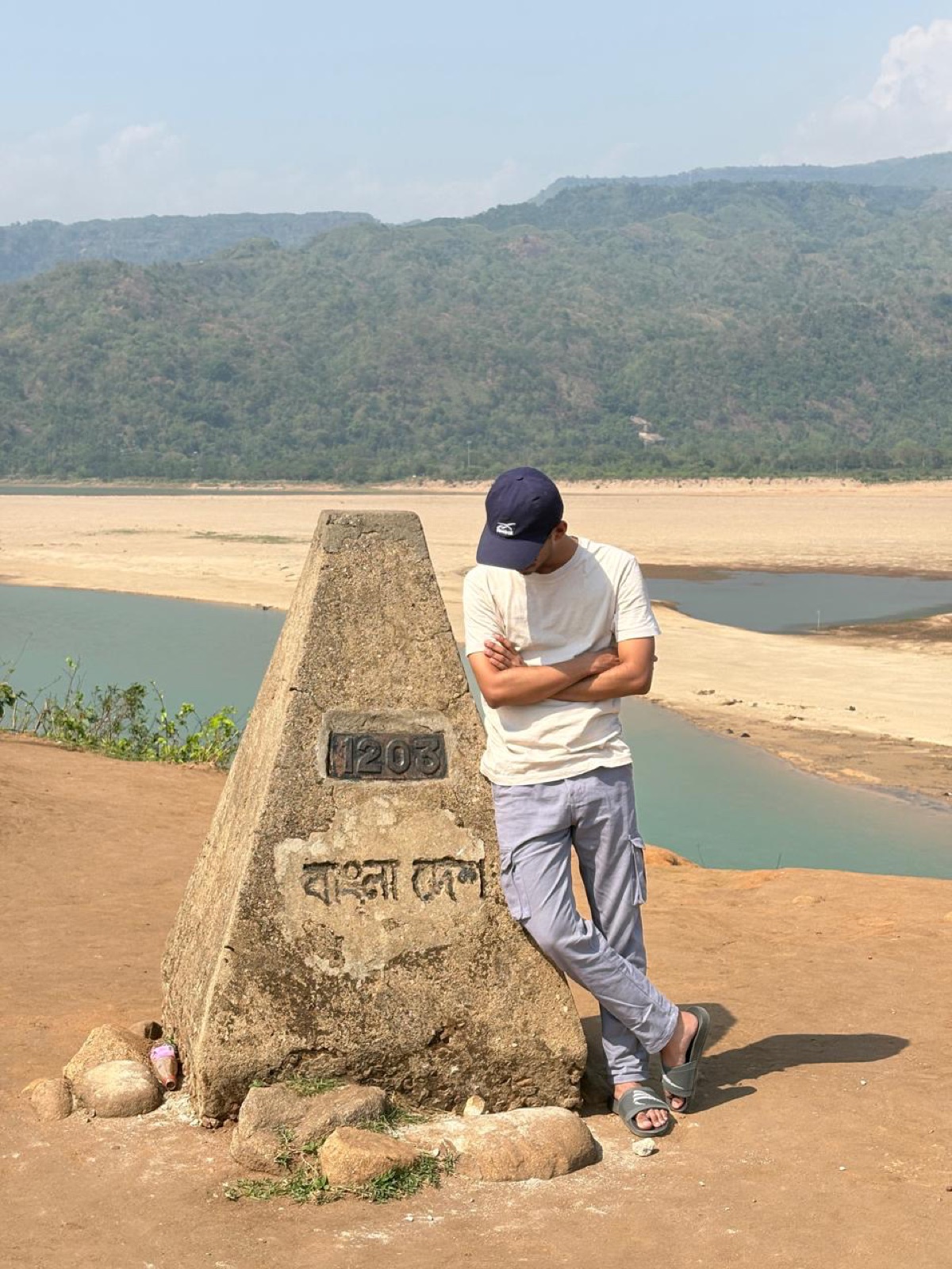 Standing beside a stone border marker numbered 1203
