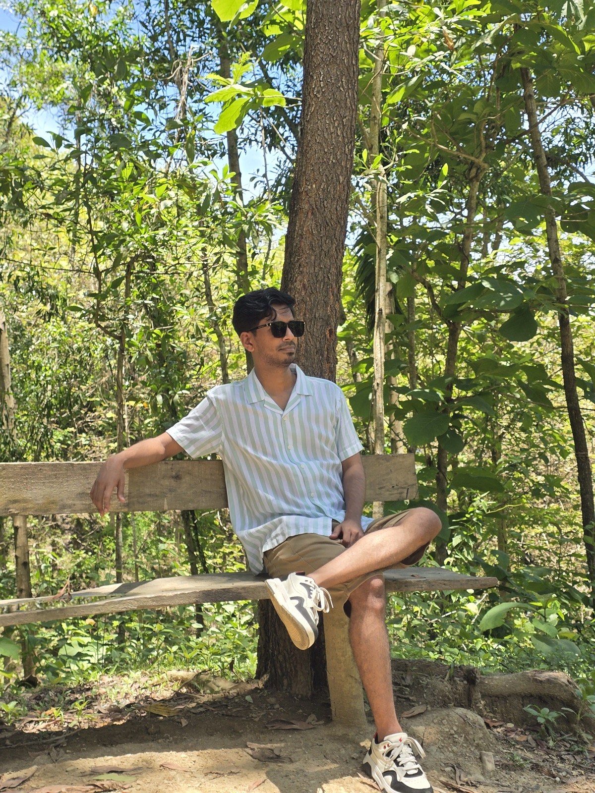 Leaning against a wooden rail under forest canopy