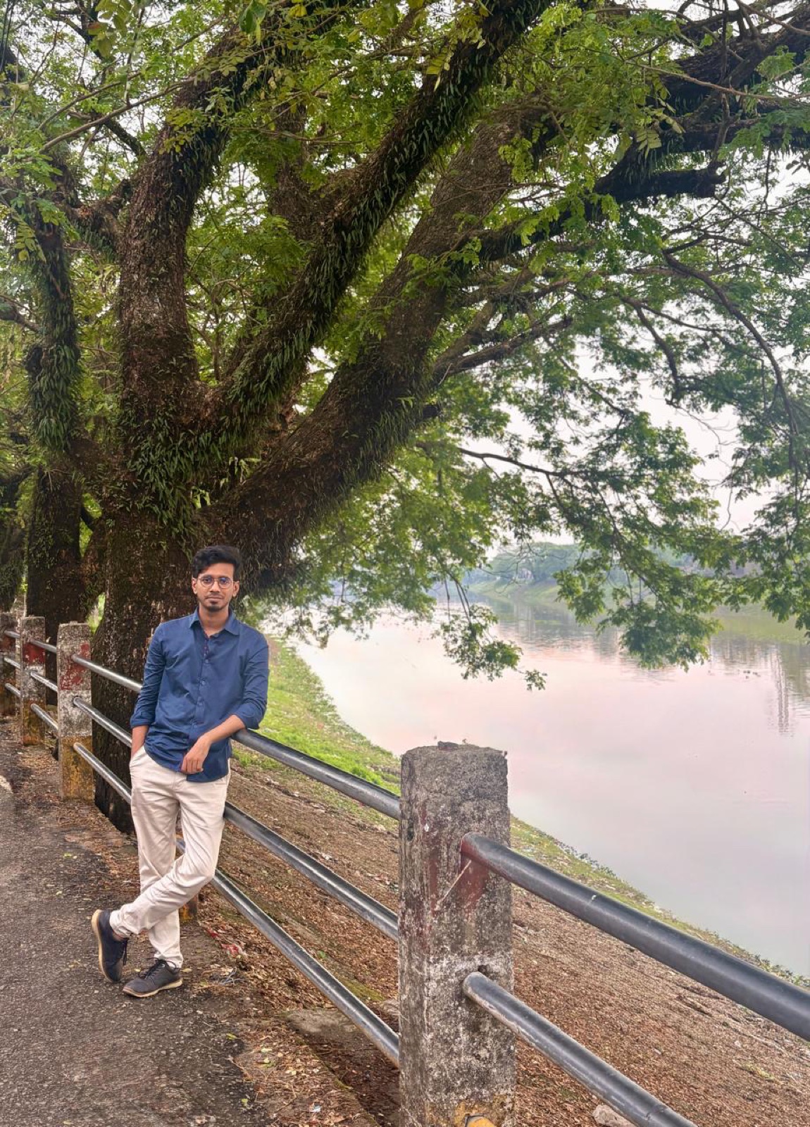 Leaning against a large tree beside a calm river